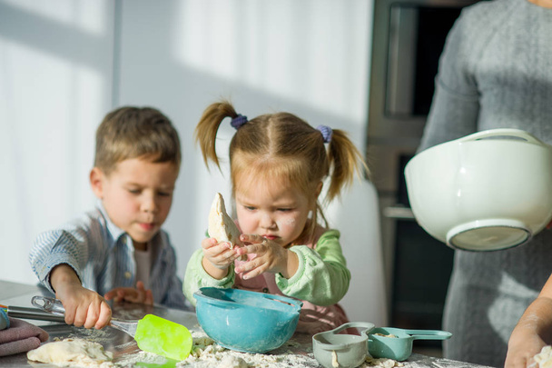 Two children are cooking something from the dough. - Фото, изображение