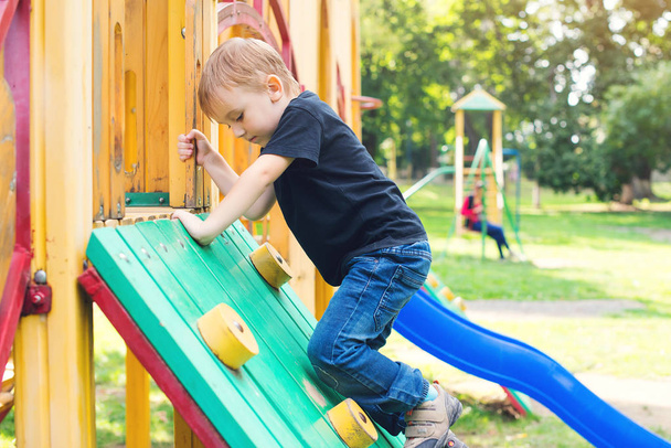 Cute little boy having fun and climbing on outdoor playground. - Photo, Image