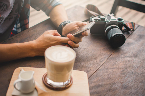 Szczęśliwy młody człowiek za pomocą smartfona w kawiarni sklep zrelaksować się razem na wakacje, kolor hipster stylu selektywne i soft focus - Zdjęcie, obraz