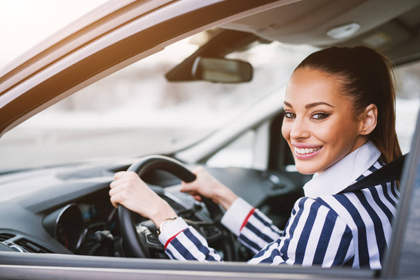 красивая улыбающаяся молодая деловая женщина за рулем автомобиля
 - Фото, изображение