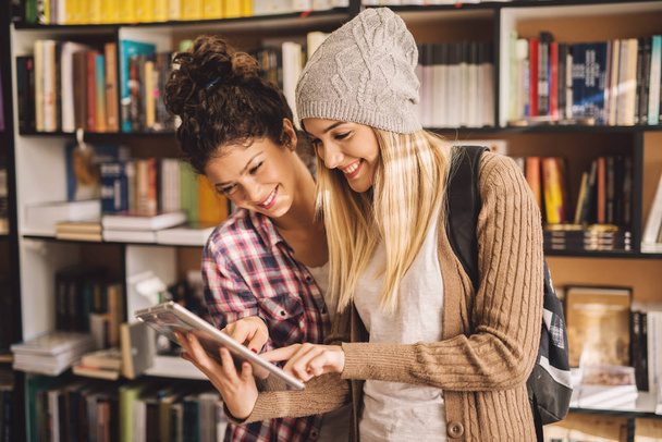 duas jovens amigas estudando na biblioteca com tablet pc, preparando-se para o exame
 - Foto, Imagem