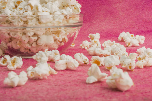 попкорн в стеклянной тарелке, на розовом фоне
 - Фото, изображение