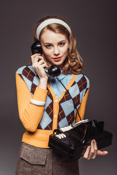 ελκυστική ρετρό στυλ κορίτσι μιλάμε τηλεφωνικώς εν στάσει vintage που απομονώνονται σε γκρι - Φωτογραφία, εικόνα