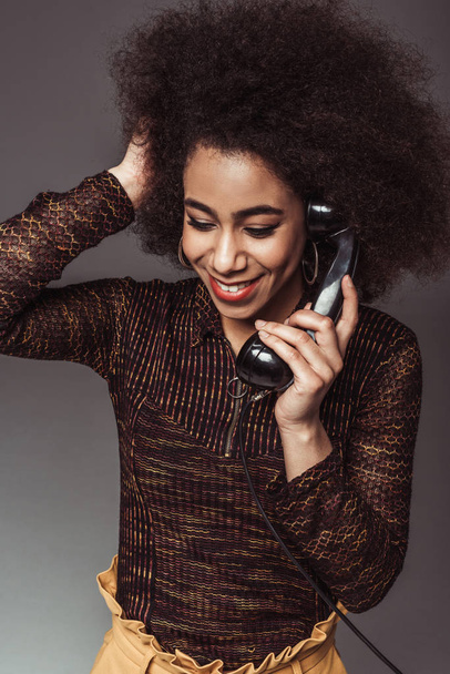 sonriente afroamericano retro chica de estilo hablando por teléfono estacionario vintage aislado en gris
 - Foto, Imagen
