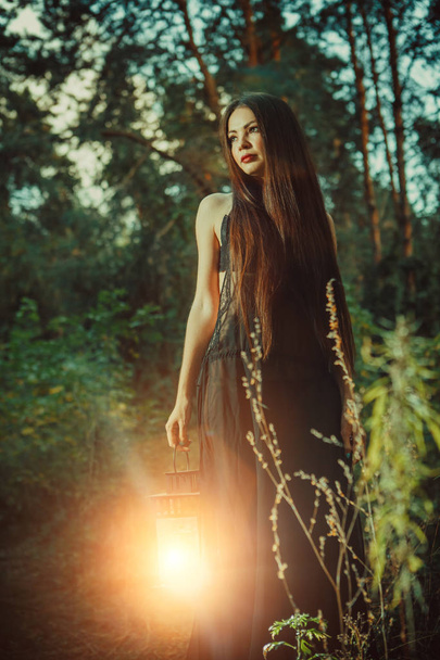 Piękna czarownica z magic lantern zaprasza do lasu. - Zdjęcie, obraz