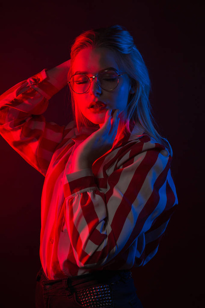 hinreißendes junges Model in Brille posiert mit rotem und blauem Studio  - Foto, Bild