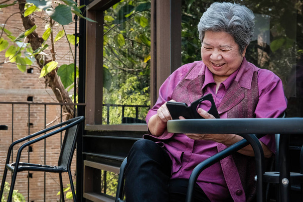 Starsza kobieta trzymając telefon komórkowy na tarasie. starszych kobiet tekstu - Zdjęcie, obraz