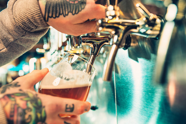Hand of bartender pouring a large lager beer in tap. - Foto, Imagen