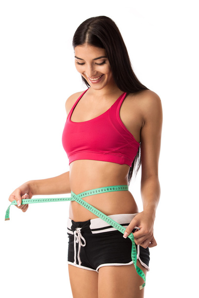 Beautiful young girl checking her waistline with a measuring tape - Foto, imagen