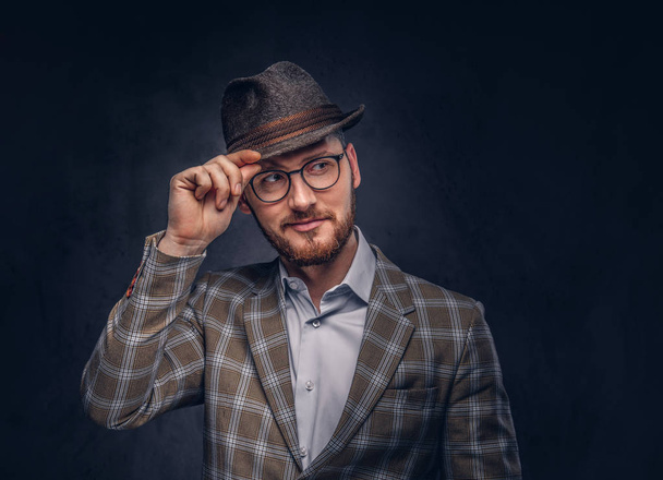 Studio portrait of a bearded hipster in hat and glasses wearing  casual suit. - Photo, Image