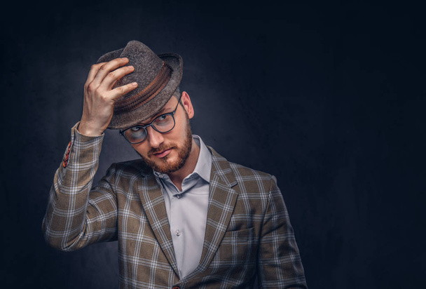 Retrato de estudio de un hipster barbudo con sombrero y gafas con traje casual
. - Foto, Imagen