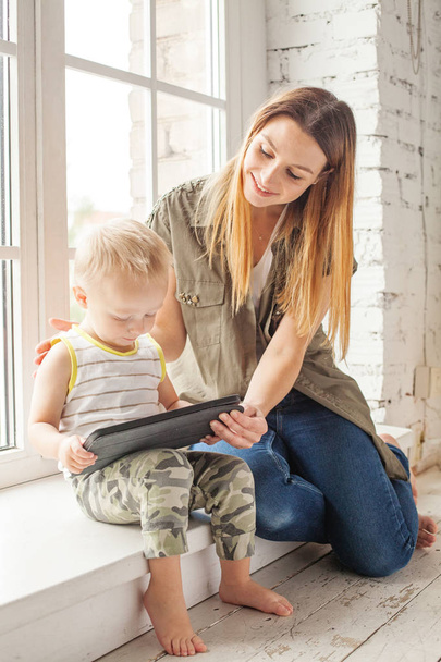Χαρούμενη μαμά και γιος χρησιμοποιώντας ψηφιακό tablet στο σπίτι. Ευτυχισμένη οικογένεια  - Φωτογραφία, εικόνα