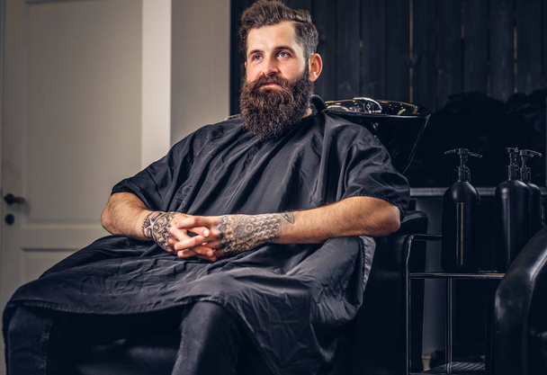 Kollarını bir kuaför salonu saç yıkama önce bir dövme ile yakışıklı sakallı erkek. - Fotoğraf, Görsel