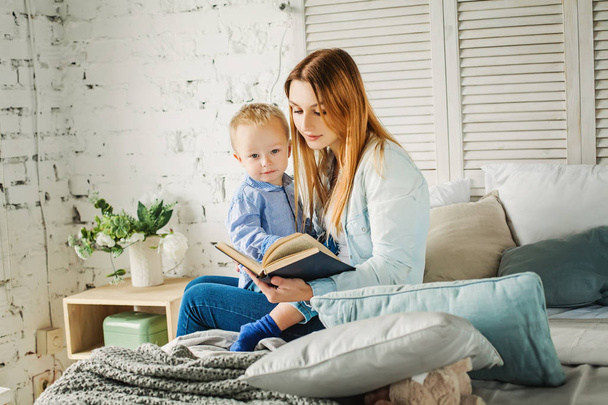 Cute Mother Reading a Book to her Son at Home. - Foto, Bild