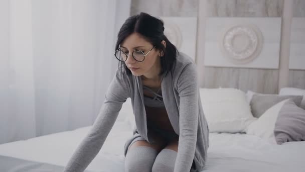Young beautiful girl is sitting on bed and takes a white tray in which a delicious breakfast and an interesting book. Healthy food - Filmagem, Vídeo