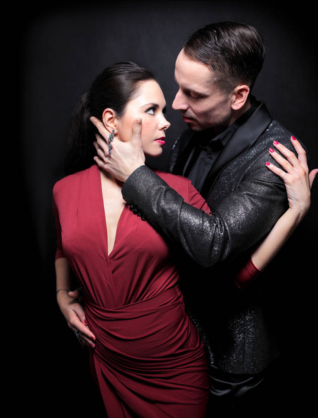 Attractive couple of professional dancers dancing passionate tango on dark background - Photo, image