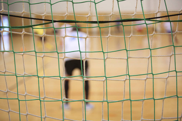 Rear view of futsal goalkeeper with net of gates foreground - 写真・画像