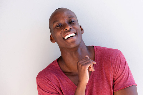 白い壁で笑って幸せな若い黒人男性の肖像画を間近します。 - 写真・画像