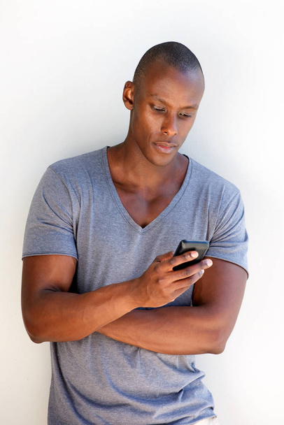 Portrait of cool black guy leaning against wall using mobile phone - Foto, Imagem