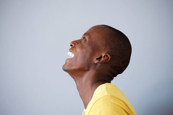 Gülüyor ve gri arka plan bakarken mutlu bir adam portresi profili  - Fotoğraf, Görsel