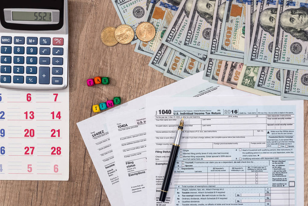 налоговая форма с деньгами, деревянные кубики, ручка, календарь и калькулятор
. - Фото, изображение