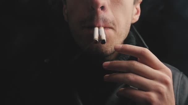 Close-up van jonge man rookt twee sigaretten tegelijk. - Video
