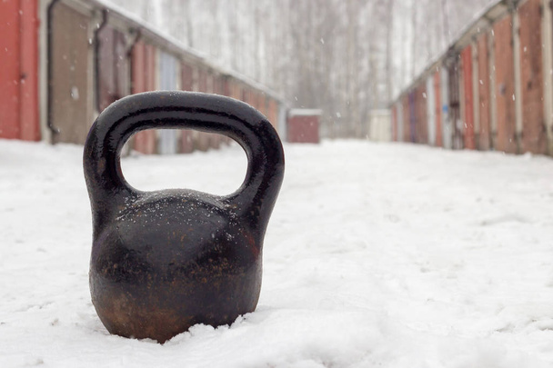 Vecchio kettlebell pesante arrugginito per l'allenamento invernale su strada bianca coperta di neve nella comunità garage
 - Foto, immagini