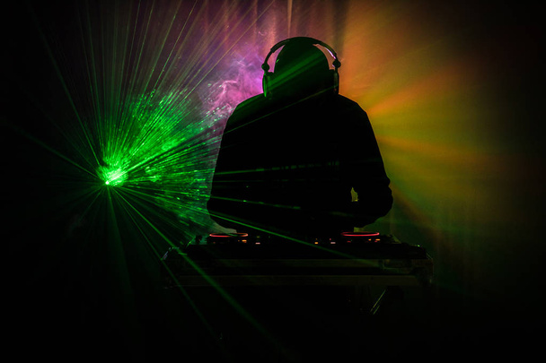 DJ Spinning, Mixing, and Scratching in a Night Club, Hands of dj tweak various track controls on dj 's deck, strobe lights and fog, or Dj mixes the track in the nightclub at party
 - Фото, изображение