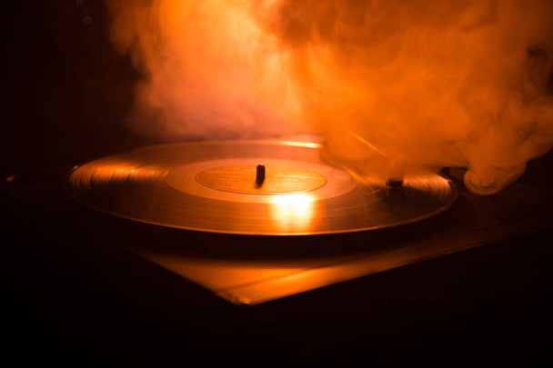 Turntable vinyl record player. Retro audio equipment for disc jockey. Sound technology for DJ to mix & play music. Vinyl record being played against burning fire background - Photo, Image