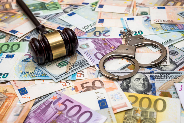 έννοια εγκλήματος - χειροπέδες, σφυρί του δολαρίου και του ευρώ τους λογαριασμούς - Φωτογραφία, εικόνα