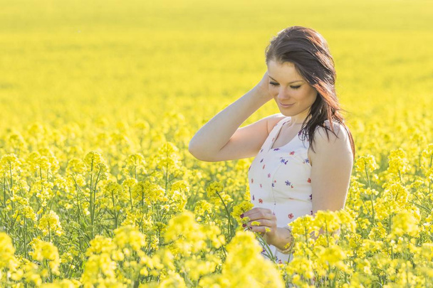 Mulher jovem beatiful com flor no prado do verão que olha para baixo
 - Foto, Imagem
