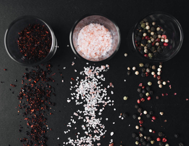 copos com sabor a sal, pimenta variada e especiarias vermelhas no fundo preto
 - Foto, Imagem