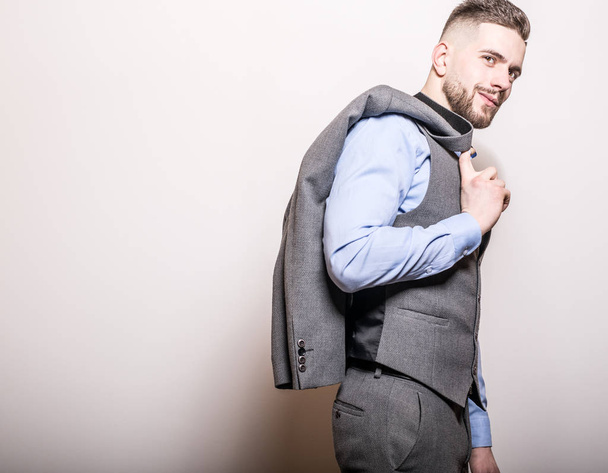 Handsome young elegant man in grey classic vest pose against studio background. - Φωτογραφία, εικόνα