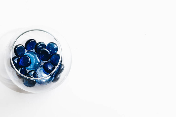 pila de pequeñas piedras azules en jarrón de vidrio aislado sobre fondo blanco
 - Foto, Imagen