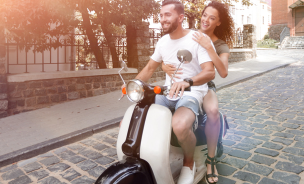 Stylish young couple sits a scooter in the street. - 写真・画像