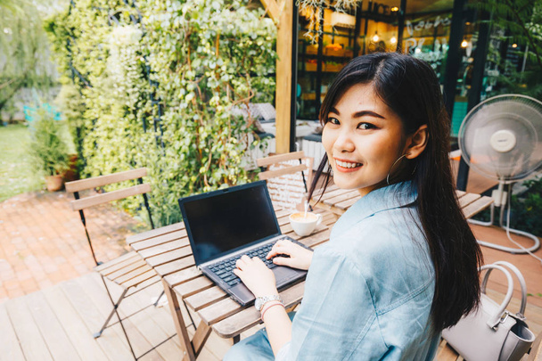 Frauen nutzen Laptop für geschäftliche Kommunikation auf Holztisch im Garten - Foto, Bild