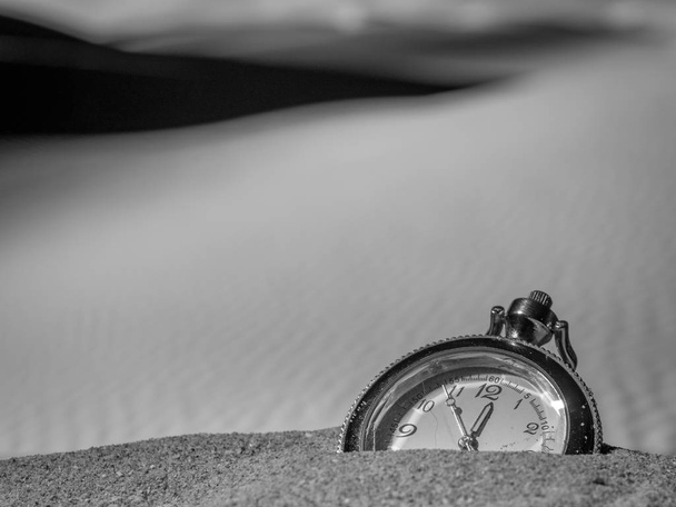 Reloj de bolsillo enterrado en la arena del desierto
 - Foto, imagen