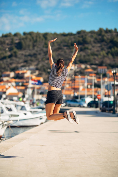Over exited happy woman jumping in the air out of happiness.Vacation time concept.Seaside coastal vacation excitement.Woman in joy got good news.Rejoicing,full of life.Summer female active,energetic - Photo, Image