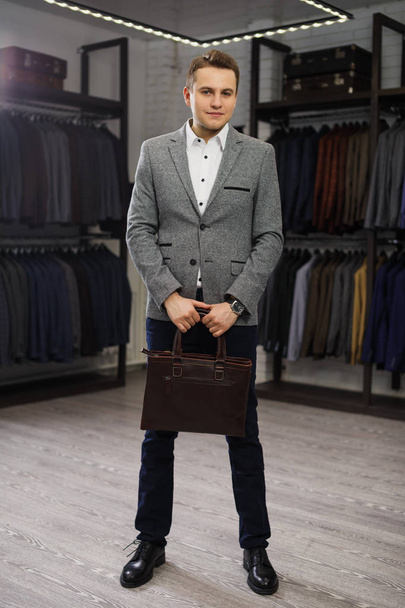 Handsome man stands in suit shop fashionable rich male dressed in expensive clothes posing indoors - Photo, Image