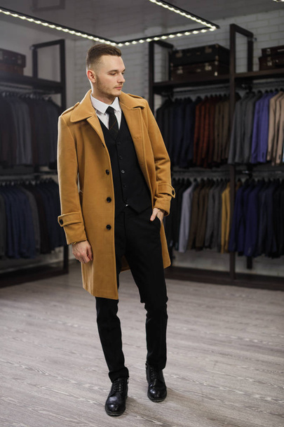 Young handsome man in coat in suit shop - Фото, зображення