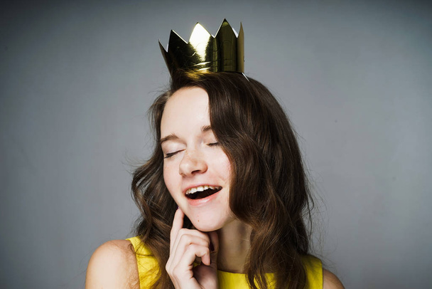happy beautiful girl in a yellow dress smiles, on her head a golden crown, celebrates Mother's Day - Foto, Bild