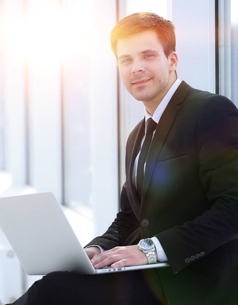 young professional with laptop on background of office window - Photo, Image