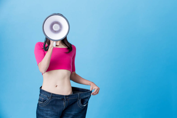 woman with megaphone  showing  weight loss on the blue background - Foto, Bild