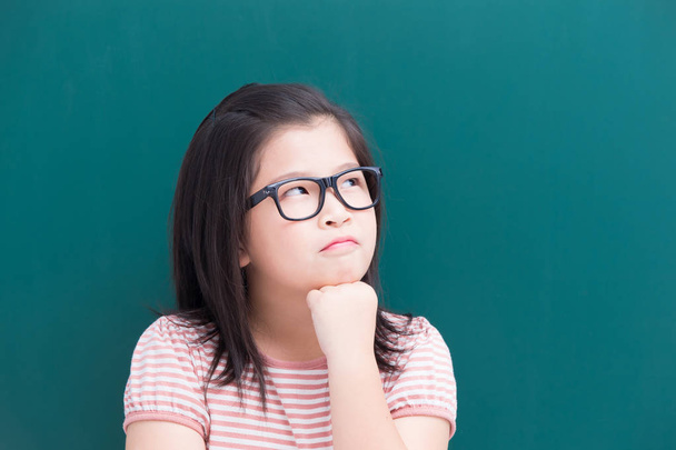 unhappy girl thinking about  something with green chalkboard  background - Foto, Imagen