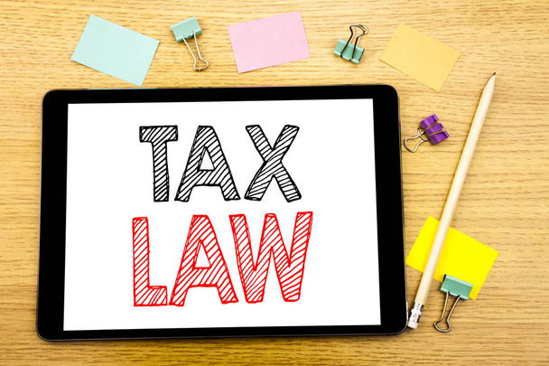 税法を示すテキストを書きます。タブレット ノート パソコンに書かれた課税税規則、付箋とペンの木製の背景のため事業コンセプト - 写真・画像
