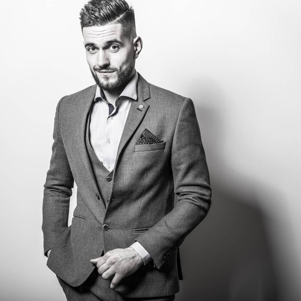 Handsome young elegant man in grey classic vest pose against studio background. - Foto, afbeelding