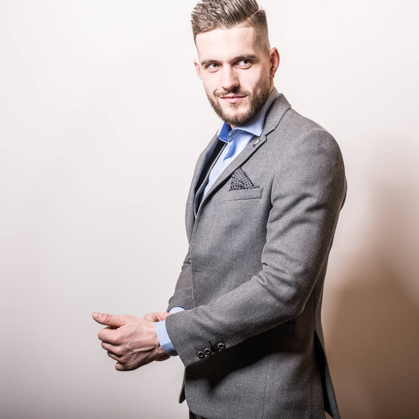 Handsome young elegant man in grey jacket pose against studio background. - Foto, imagen
