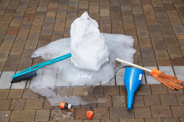 Restos de muñeco de nieve derretido en la losa de pavimentación
 - Foto, Imagen