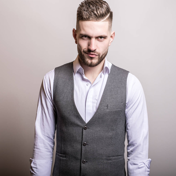 Handsome young elegant man in grey classic vest pose against studio background. - Фото, зображення