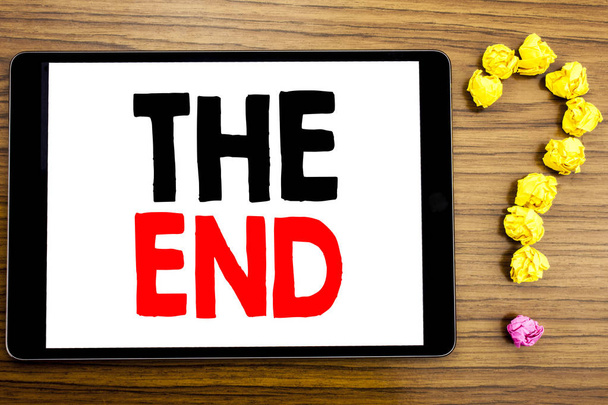 Tekst intoetsen met The End. Businessconcept voor einde Finish sluiten als geschreven op tablet pc op de houten achtergrond met vraagteken gemaakt van gevouwen papier. - Foto, afbeelding